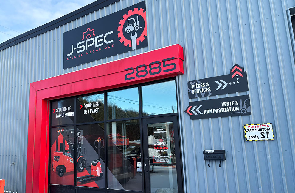 Vue de la devanture extérieur du commerce de J-SPEC atelier mécanique avec panneaux directionnels pour les différentes portes, panneau du logo et wrap partiel de la vitrines incluant les services offers et des photos des équipements